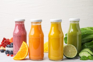 Photo of Glass bottles of tasty smoothies and different products on white table