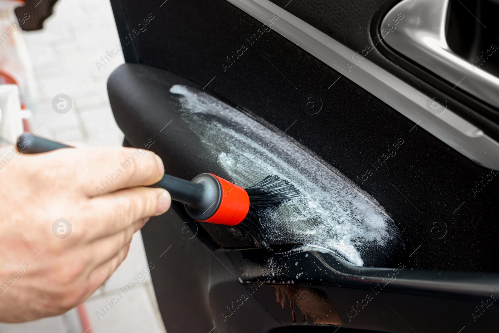 Photo of Man cleaning car door with brush outdoors, closeup