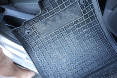 Photo of Man taking black rubber car mat from auto, closeup