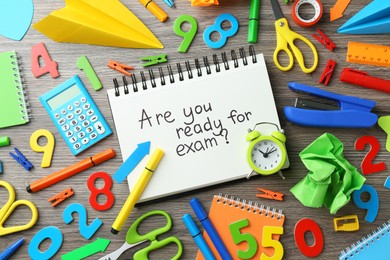 Notepad with question Are You Ready For Exam and stationery on wooden desk, flat lay