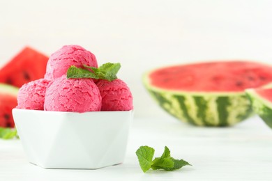 Photo of Scoops of tasty watermelon sorbet with mint in bowl on white table, closeup. Space for text