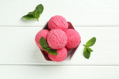 Scoops of tasty watermelon sorbet with mint in bowl on white wooden table, flat lay