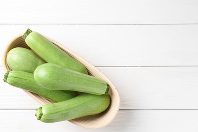 Photo of Fresh zucchinis on white wooden table, top view. Space for text