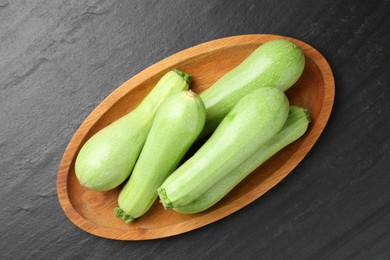 Photo of Fresh zucchinis on dark textured table, top view