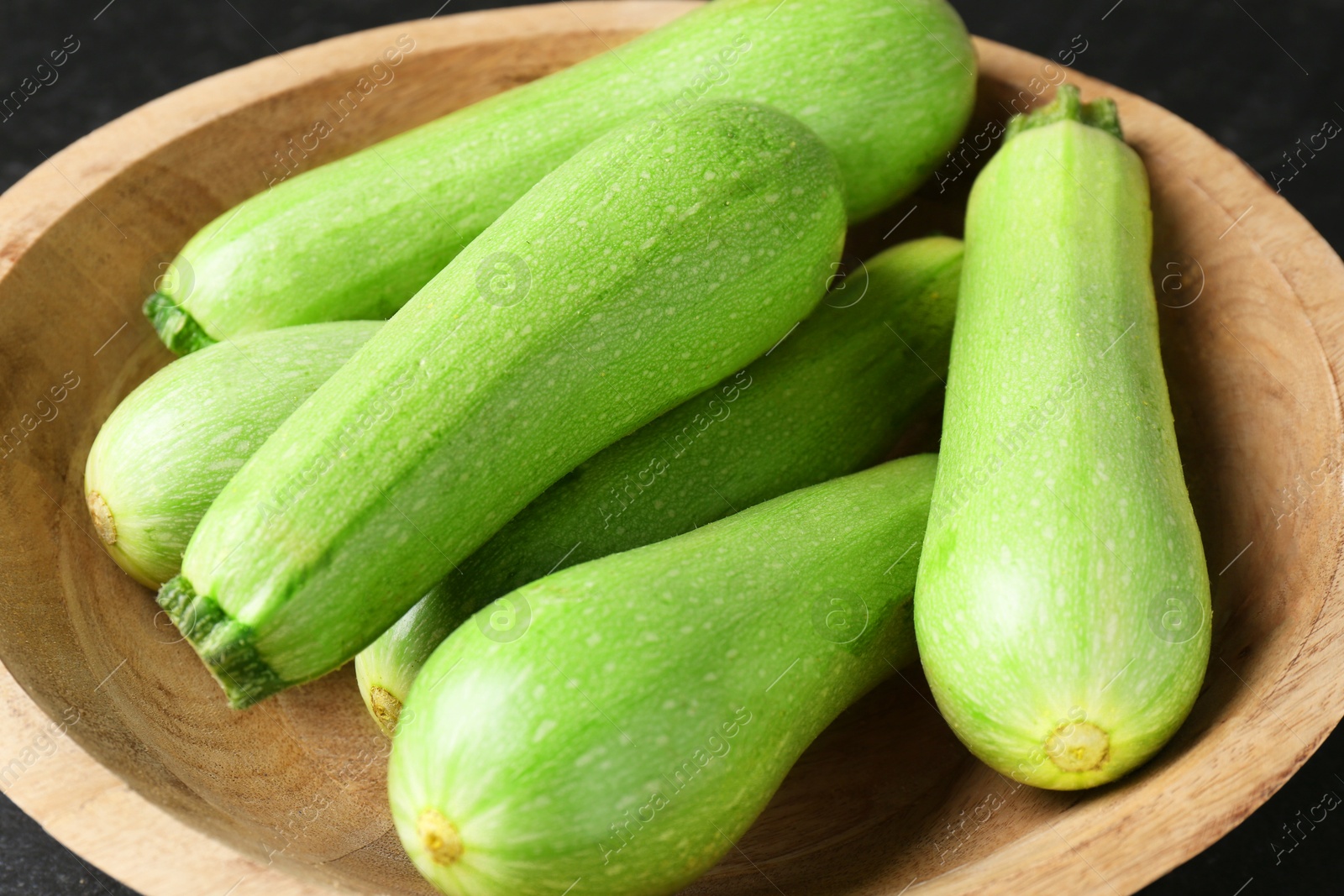 Photo of Fresh zucchinis in bowl on table, closeup