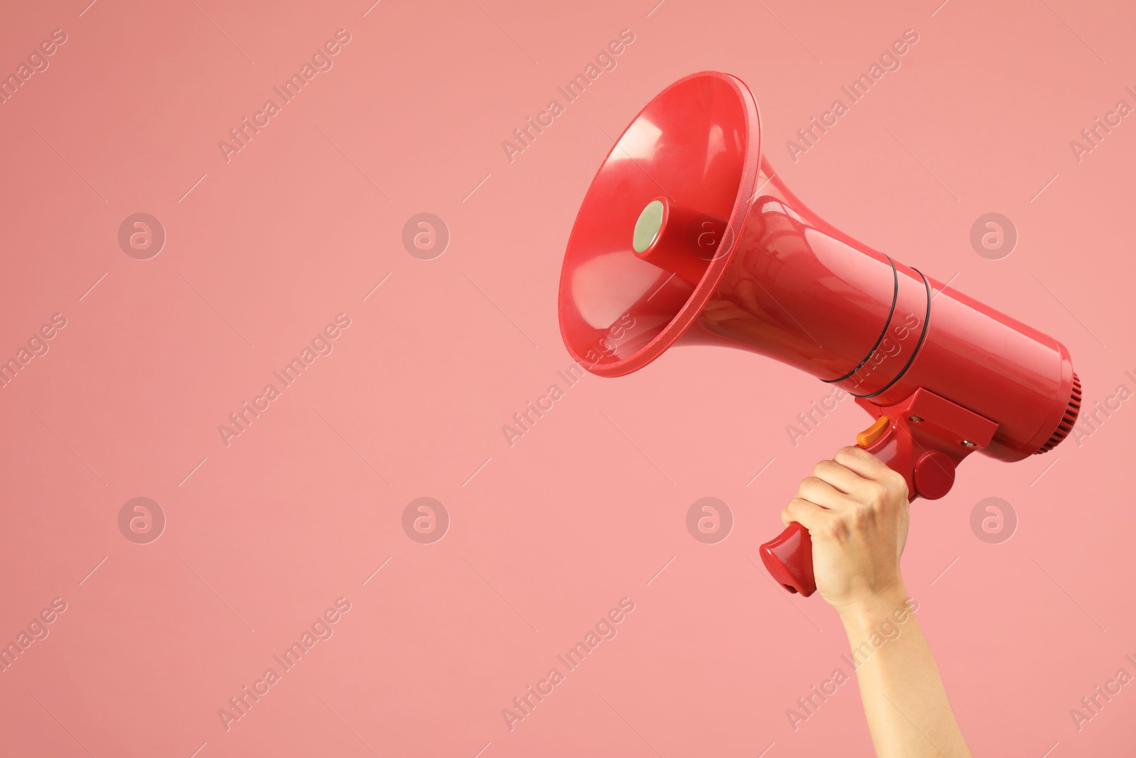 Photo of Woman holding megaphone speaker on pink background, closeup. Space for text