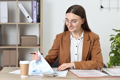 Photo of Budget planning. Beautiful young woman with papers and calculator at wooden table in office