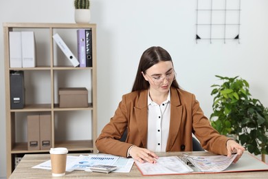 Photo of Budget planning. Beautiful young woman with papers and calculator at wooden table in office