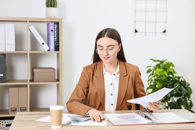 Photo of Budget planning. Beautiful young woman with papers and calculator at wooden table in office