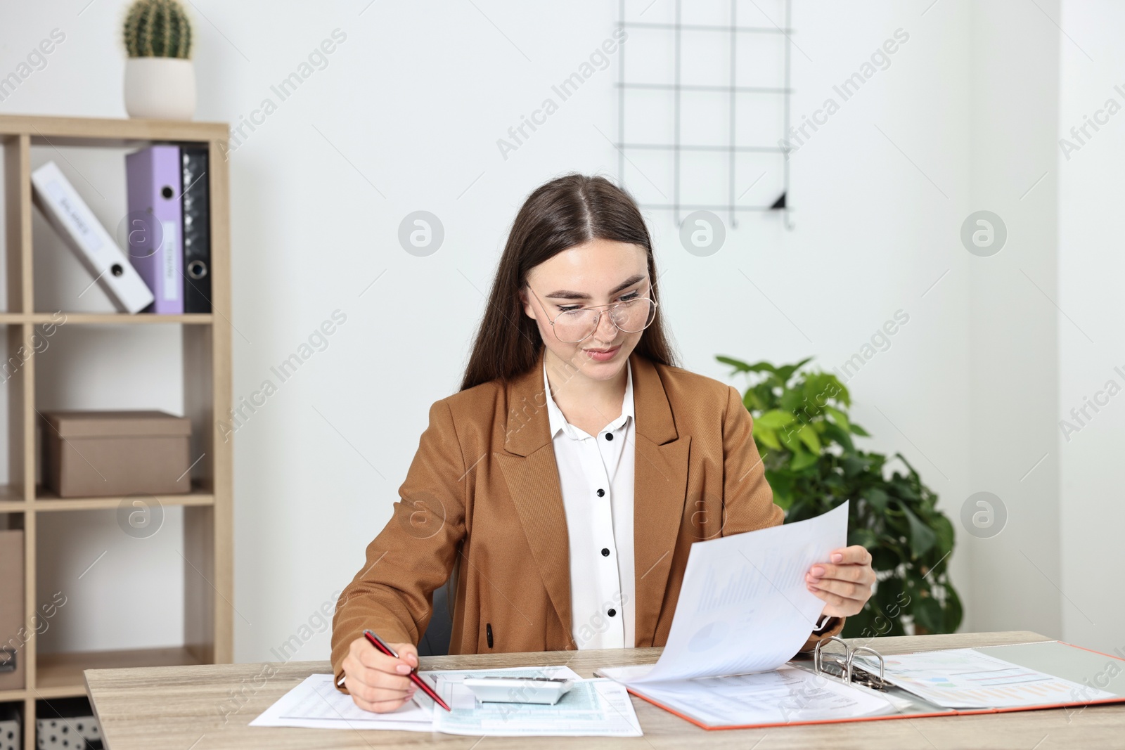 Photo of Budget planning. Beautiful young woman with papers and calculator at wooden table in office