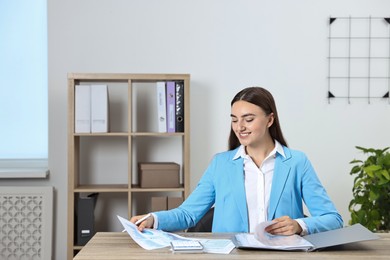 Photo of Budget planning. Beautiful young woman with papers and calculator at wooden table in office