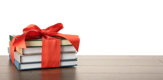 Photo of Stack of books with red ribbon as gift on wooden table against white background, space for text