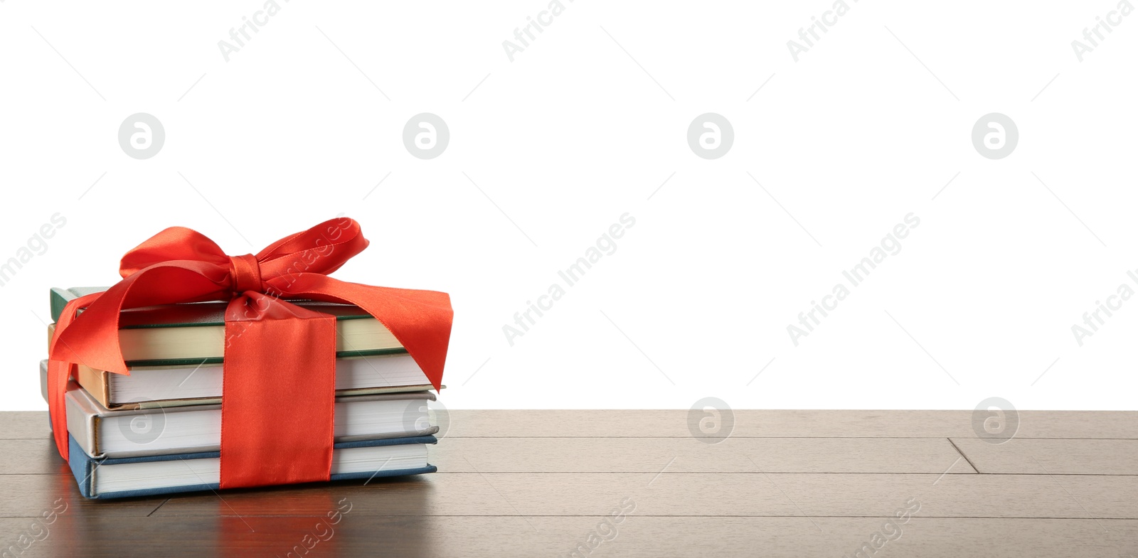 Photo of Stack of books with red ribbon as gift on wooden table against white background, space for text