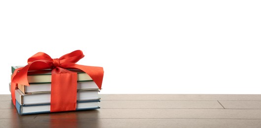 Photo of Stack of books with red ribbon as gift on wooden table against white background, space for text