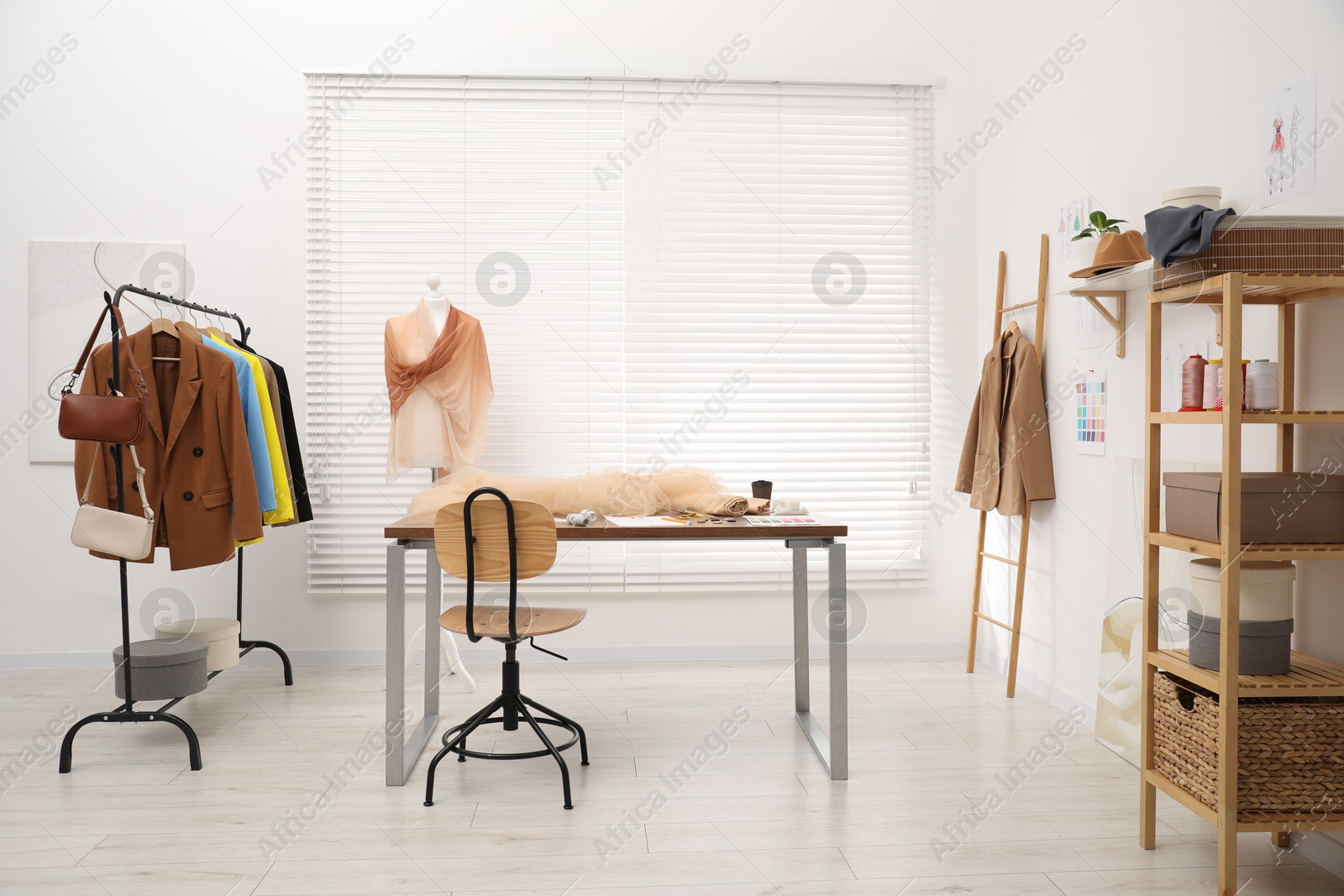 Photo of Fashion designer`s workplace with fashionable clothes, fabric samples and sewing supplies