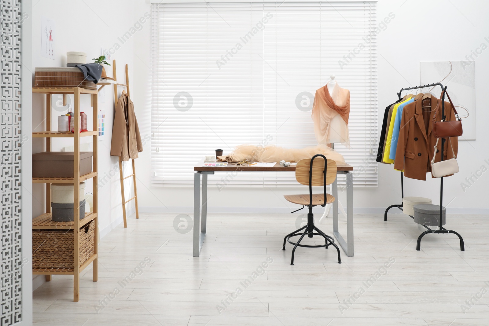 Photo of Fashion designer`s workplace with fashionable clothes, fabric samples and sewing supplies