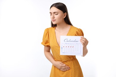 Photo of Woman holding calendar with marked menstrual cycle days and suffering from abdominal pain on white background