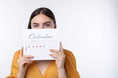 Photo of Woman holding calendar with marked menstrual cycle days on white background, space for text