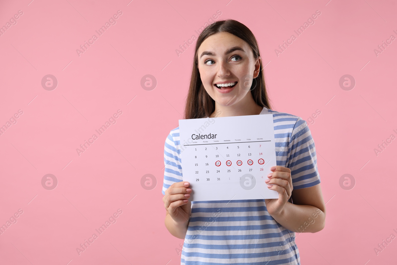 Photo of Woman holding calendar with marked menstrual cycle days on pink background, space for text