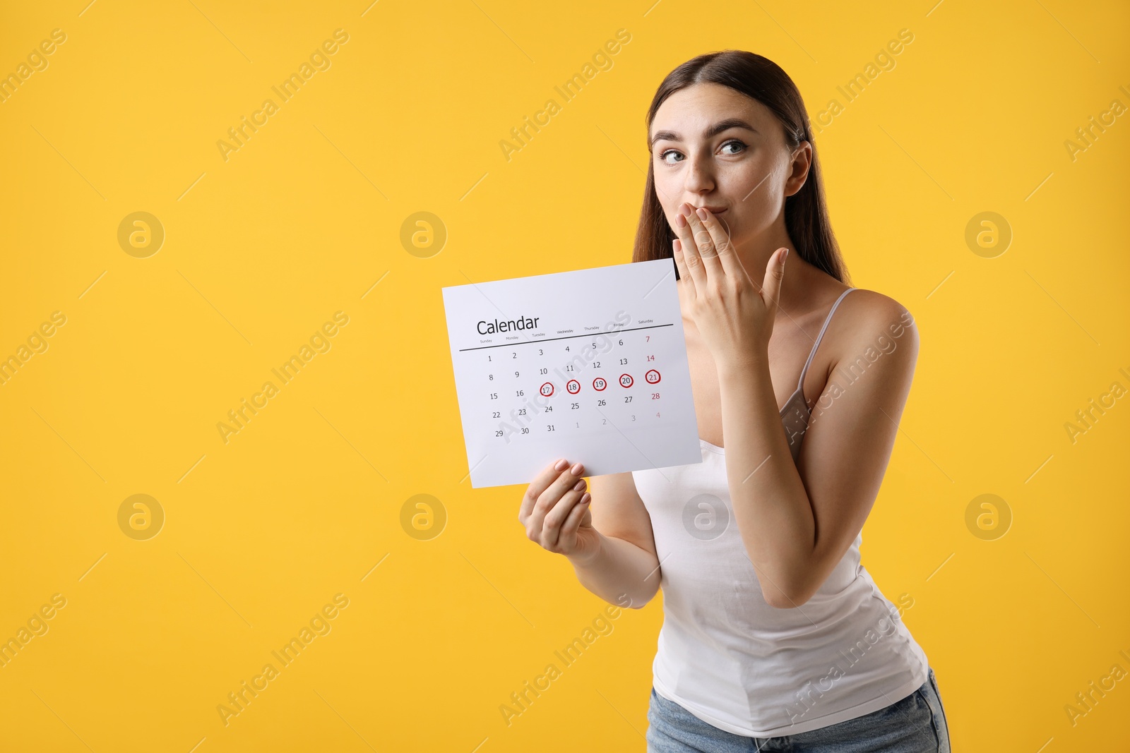 Photo of Woman holding calendar with marked menstrual cycle days on orange background, space for text