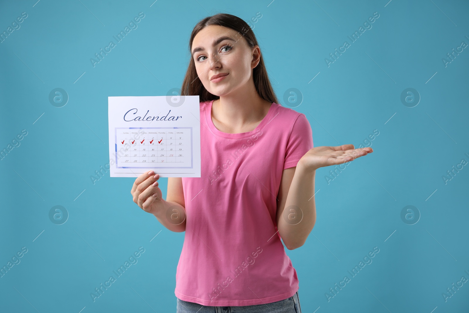 Photo of Woman holding calendar with marked menstrual cycle days on light blue background