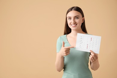 Woman holding calendar with marked menstrual cycle days on beige background, space for text