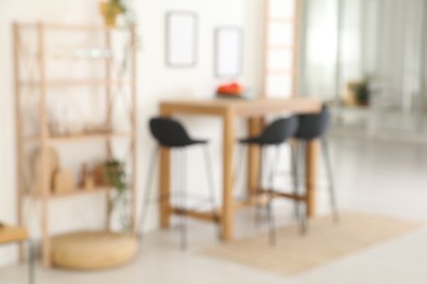 Blurred view of bar stools near wooden table in room