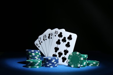 Photo of Poker chips and playing cards on blue table