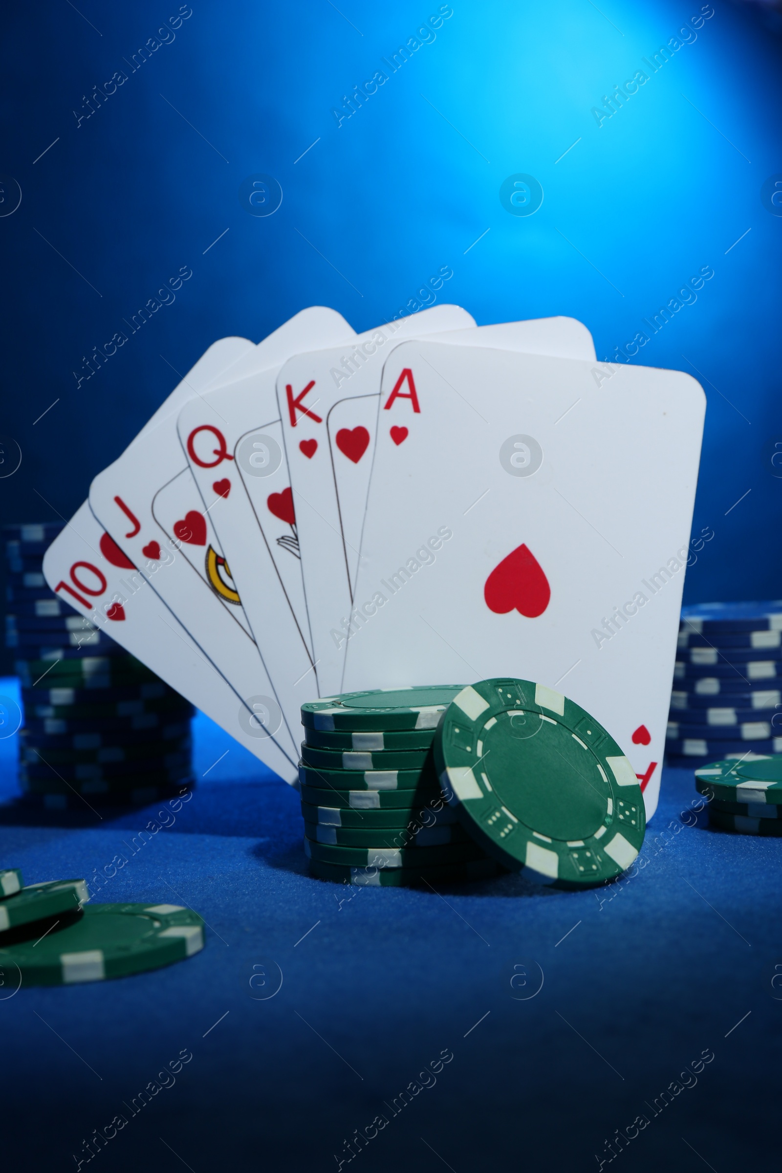 Photo of Poker chips and playing cards on blue table