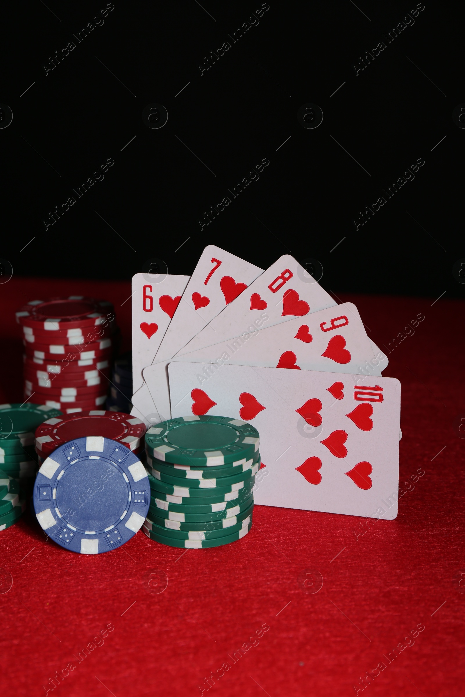 Photo of Poker chips and playing cards on red table