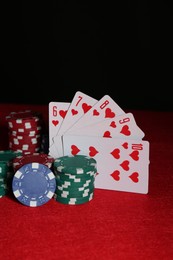 Photo of Poker chips and playing cards on red table