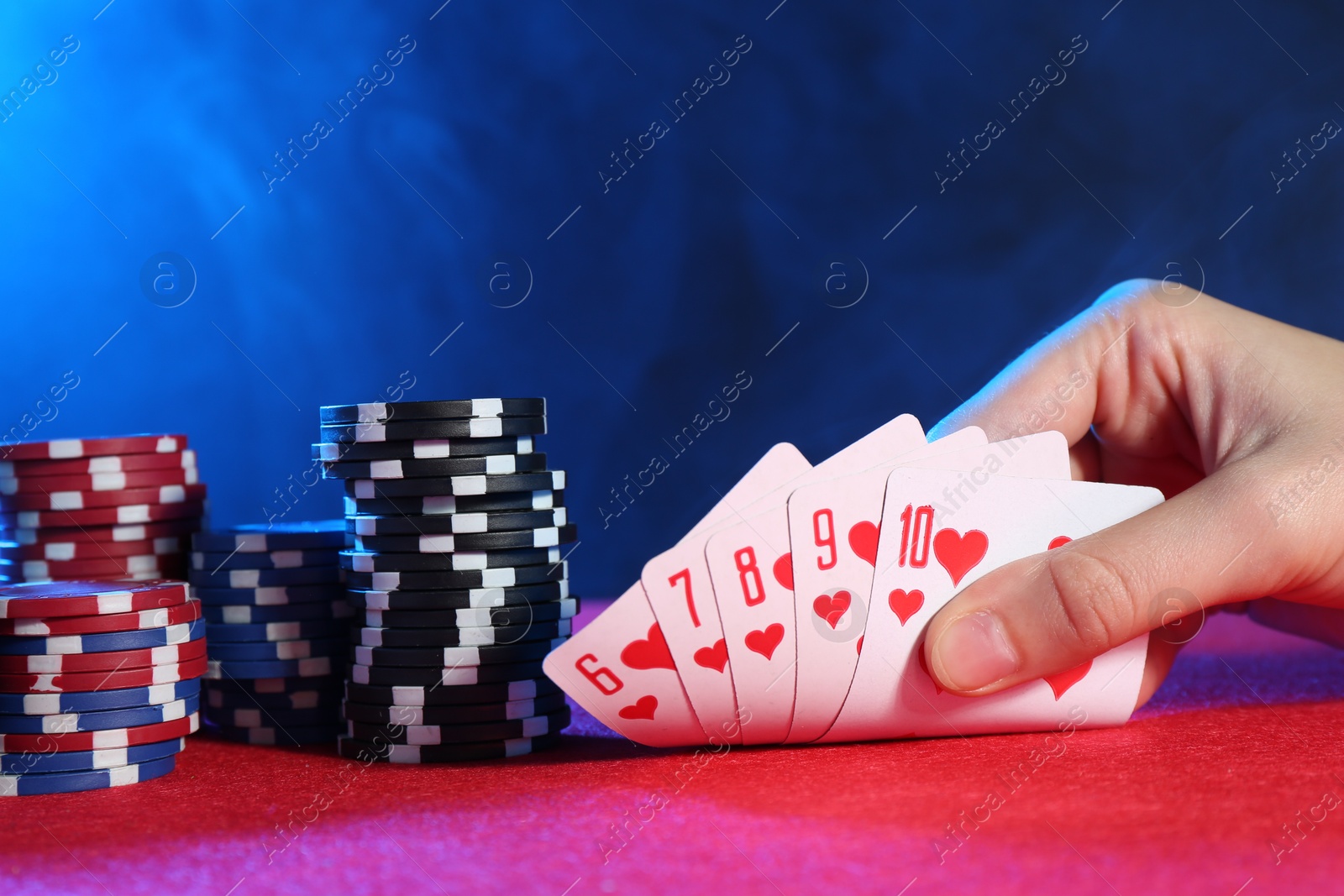 Photo of Woman with playing cards and poker chips at pink table, closeup