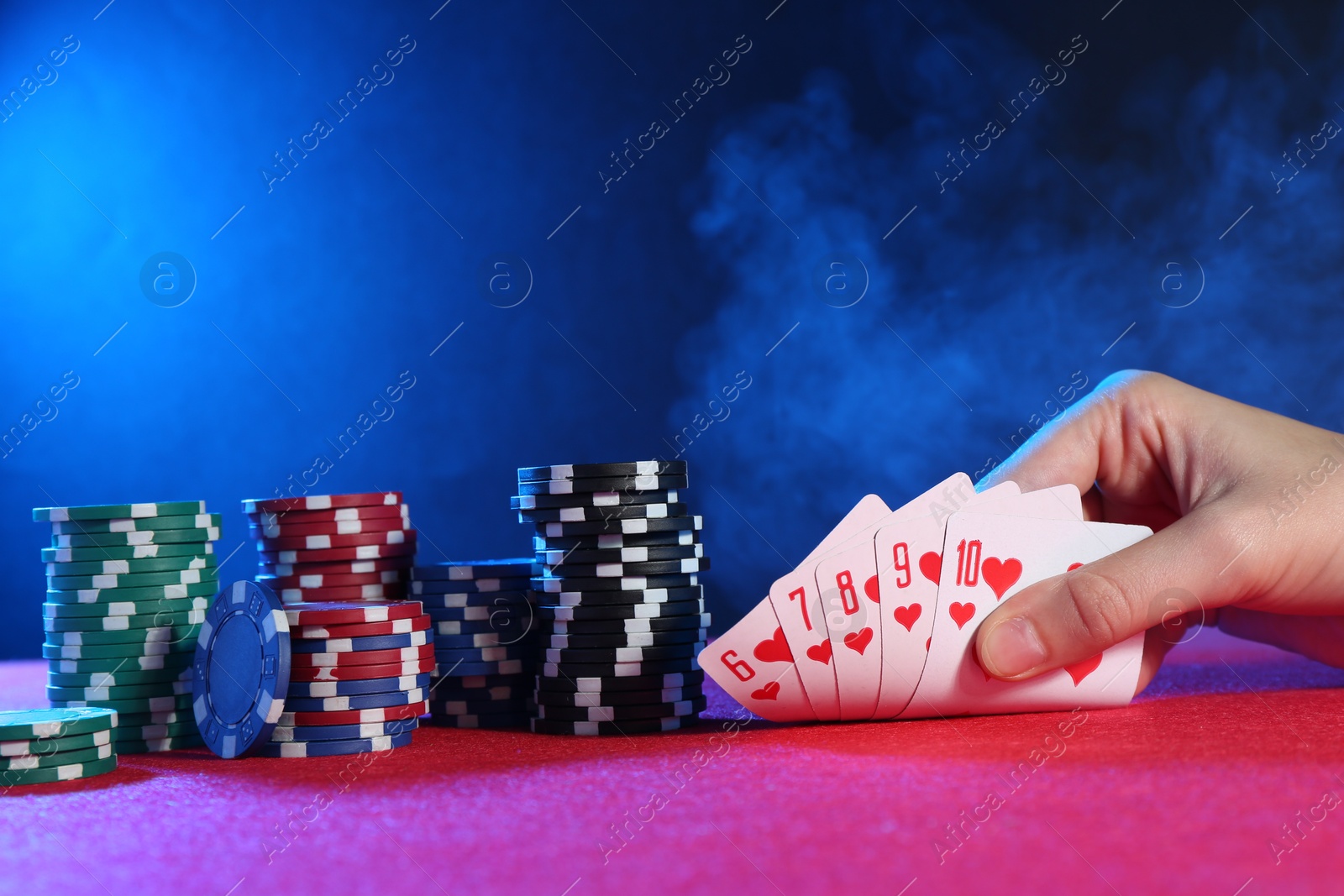 Photo of Woman with playing cards and poker chips at pink table, closeup