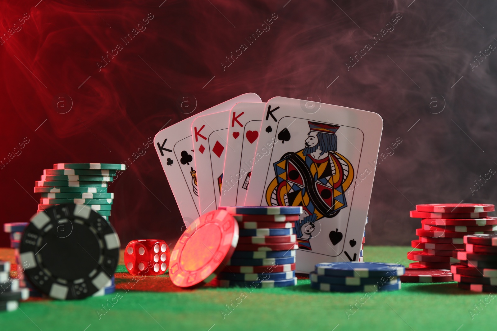 Photo of Poker chips, dice and playing cards on green table in neon lights, closeup