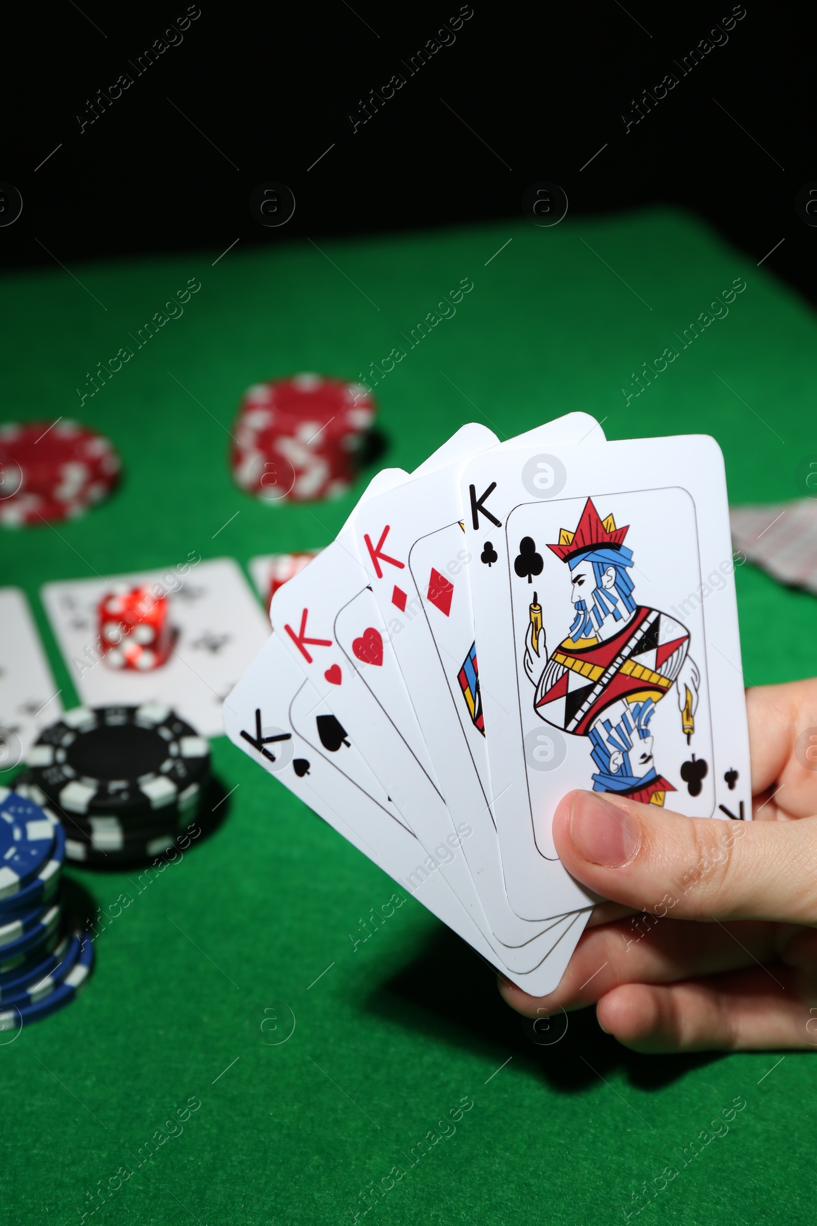 Photo of Poker game. Woman with playing cards at green table, closeup