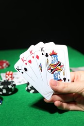 Photo of Poker game. Woman with playing cards at green table, closeup