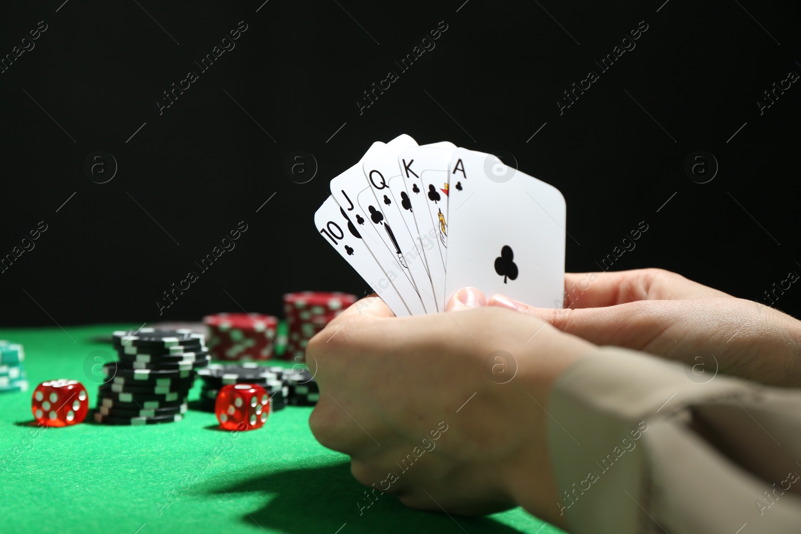 Photo of Poker game. Woman with playing cards at green table, closeup