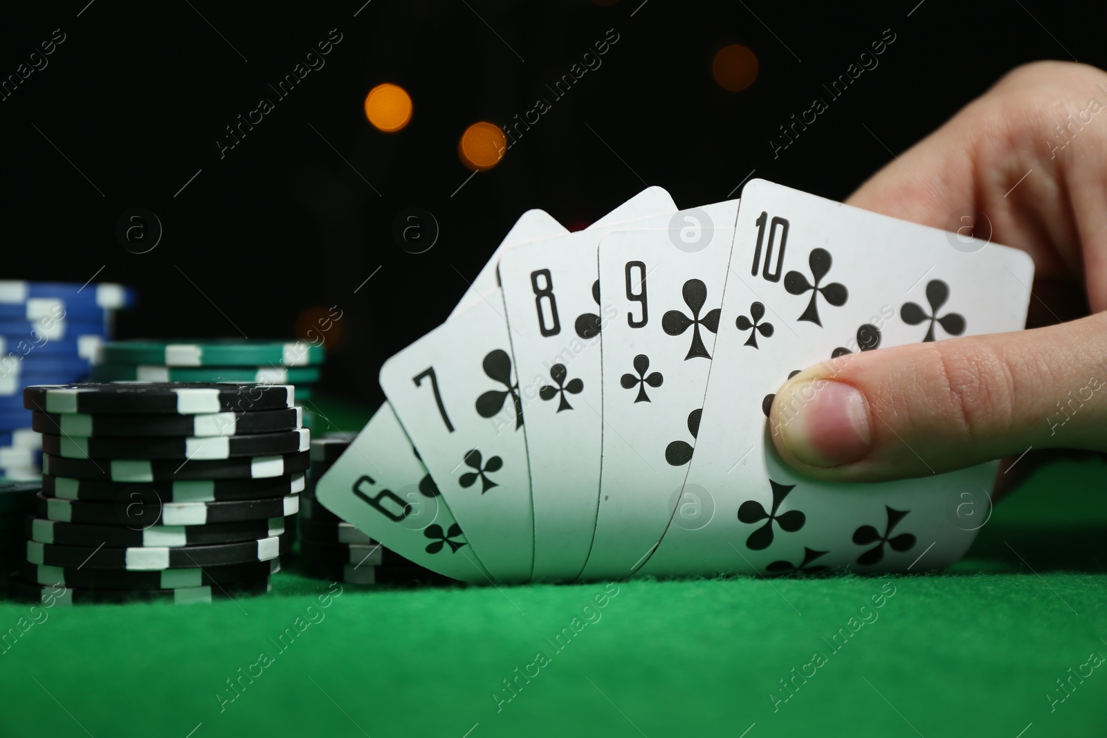 Photo of Poker game. Woman with playing cards and chips at green table, closeup