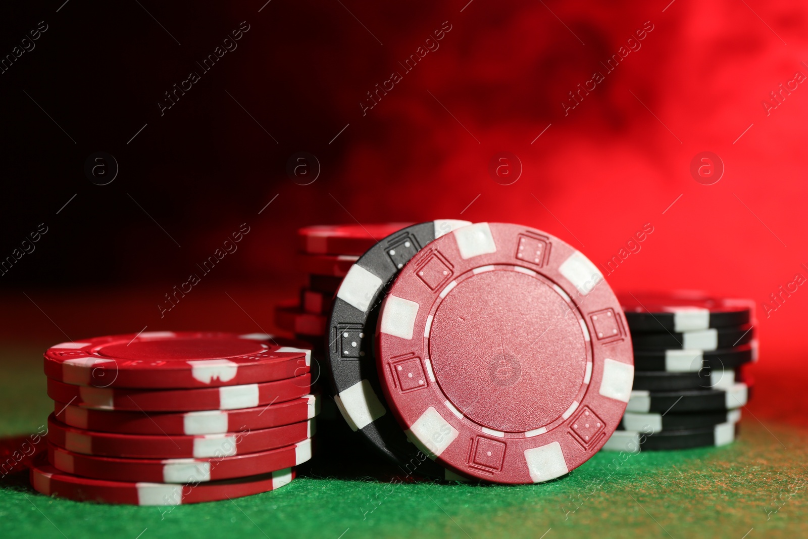 Photo of Poker game. Casino chips on green table in neon lights, closeup