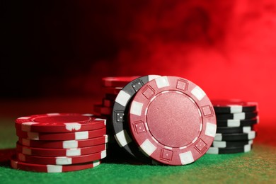 Photo of Poker game. Casino chips on green table in neon lights, closeup