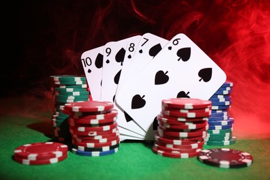 Photo of Poker chips and playing cards on green table