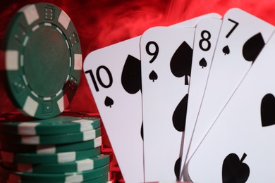 Photo of Poker chips and playing cards on color background, closeup