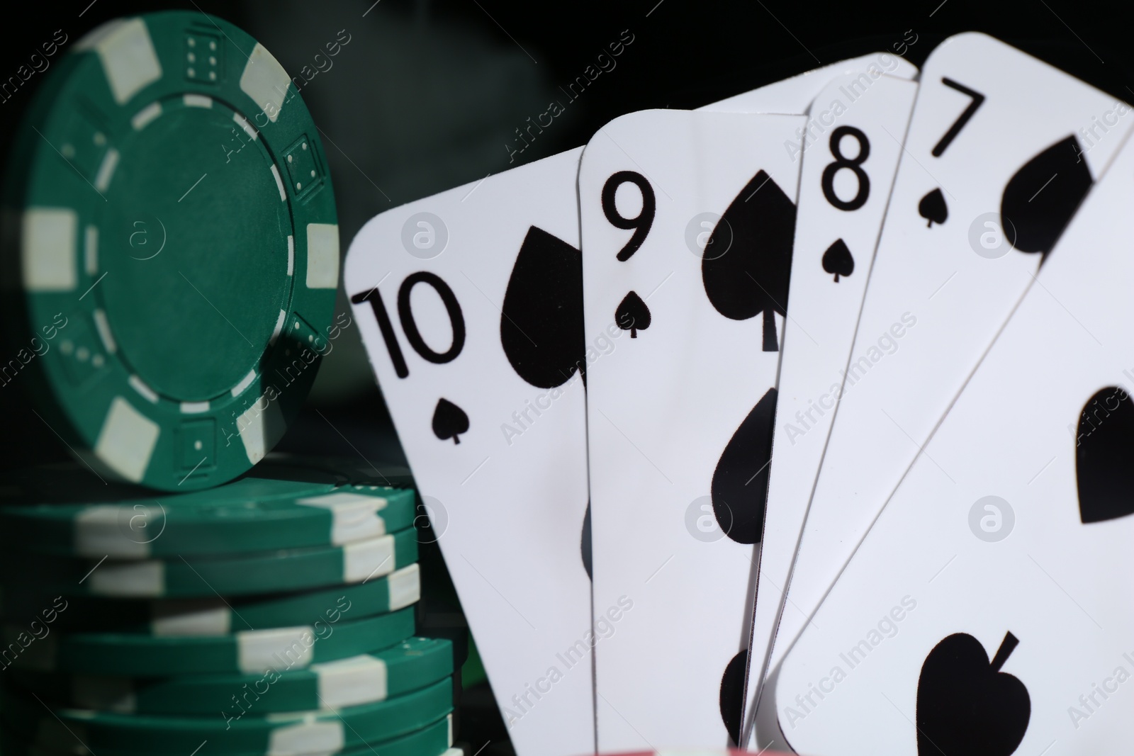 Photo of Poker chips and playing cards on dark background, closeup