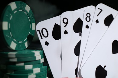 Photo of Poker chips and playing cards on dark background, closeup