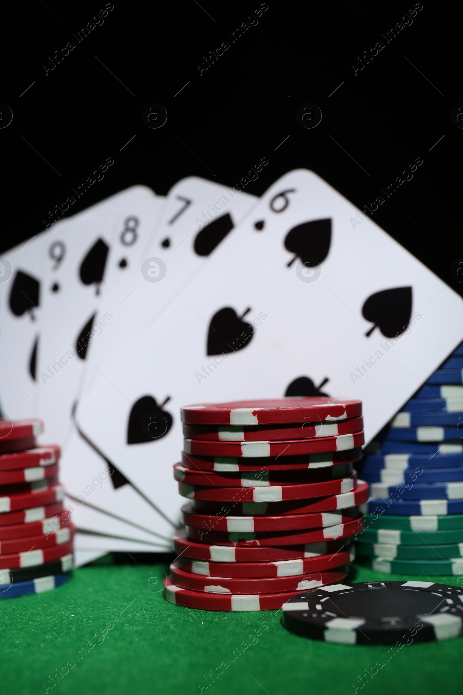 Photo of Poker chips and playing cards on green table, closeup