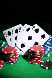 Photo of Poker chips and playing cards on green table