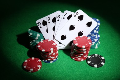 Photo of Poker chips and playing cards on green table