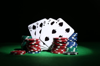 Photo of Poker chips and playing cards on green table