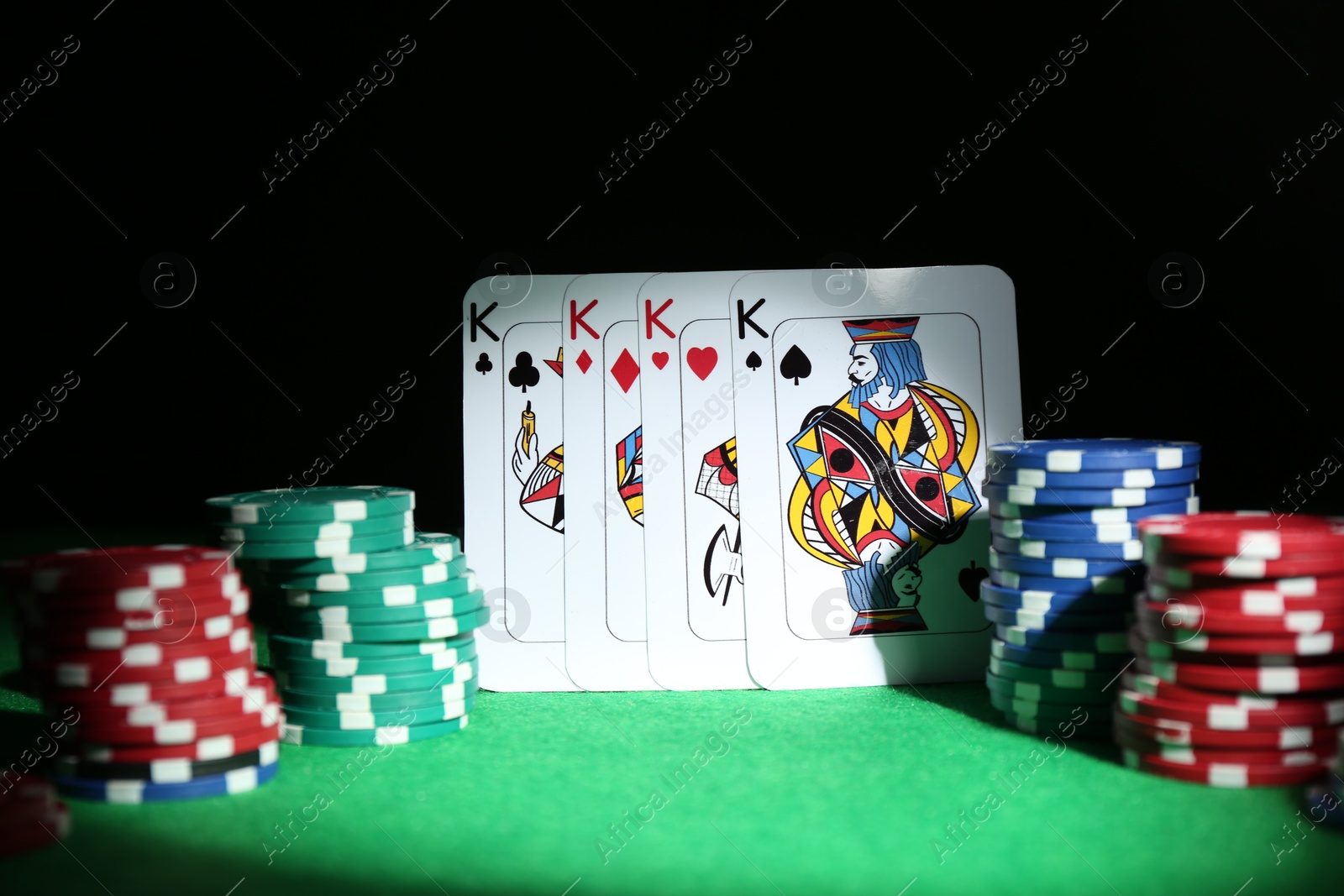 Photo of Poker chips and playing cards on green table