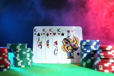 Photo of Poker chips and playing cards on green table